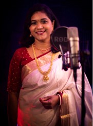 A person in a white sari and gold necklace    Description automatically generated