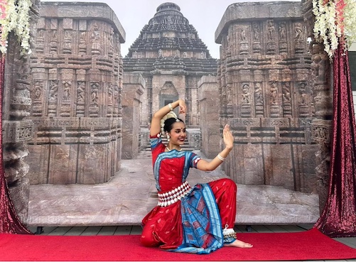 A person in traditional indian attire with Konark Sun Temple in the background    Description automatically generated